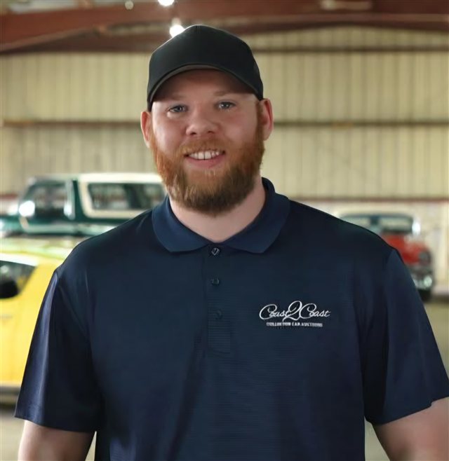 Chance Blakley, founder of BidNation, in a Coast2Coast Collector Car Auctions shirt with collector cars behind him